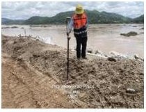 Surveyor working a riverbank cross-section with a survey pole